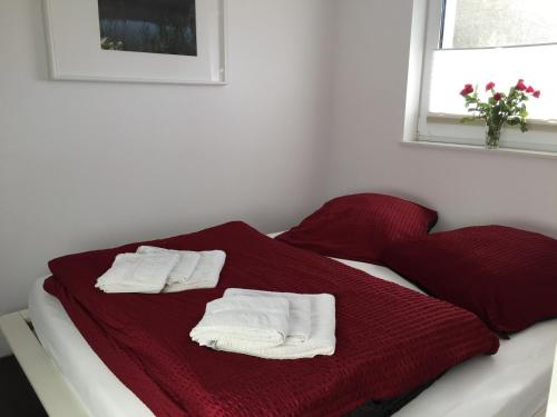 a bed with red blanket and white towels on it at Ferienwohnung Felix am See in Joachimsthal