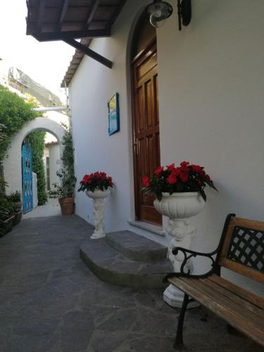 a building with a porch with a bench and flowers at Villa Loreta in Ischia