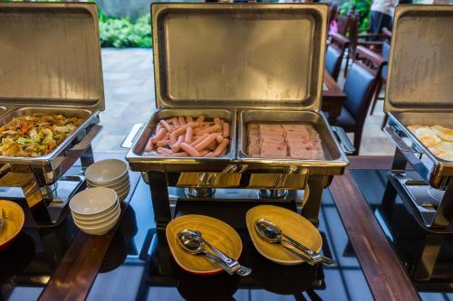 three trays of food on a table with plates at Olive Tree Hotel Pattaya in Na Jomtien