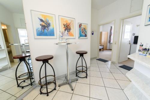 a room with three bar stools and paintings on the wall at Hotel Böving in Breckerfeld