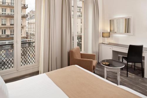 パリにあるHotel Paris Opera Affiliated by Meliáのベッド、デスク、窓が備わるホテルルームです。