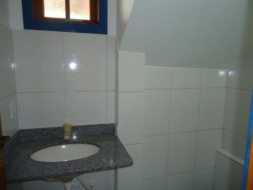 een witte badkamer met een wastafel en een raam bij Flores de Búzios Suítes in Búzios