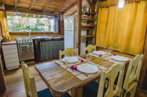 uma cozinha com uma mesa de madeira com cadeiras e um frigorífico em Morada Amazona na Praia do Rosa