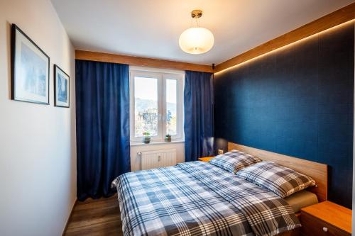 - une chambre avec un lit et un mur bleu dans l'établissement Apartament Makuszynsky, à Zakopane