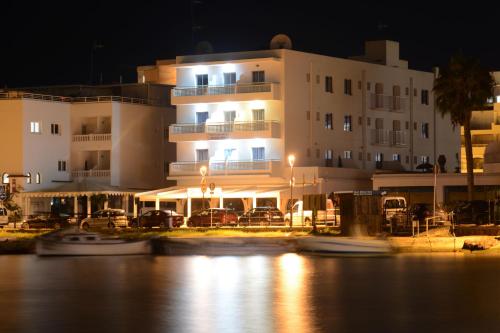 a large building with boats in the water at night at Apartamentos Playa Sol in Es Cana