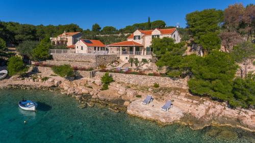 an aerial view of a house with a boat in the water at Luxury Villa Kate - in Lucice Bay with turquoise sea, Amazing Seaviews, and Heated Pool in Milna