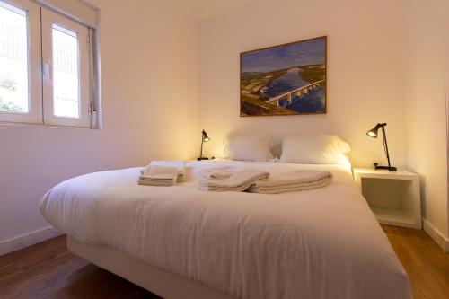 a bedroom with a white bed with towels on it at Typical Tailor Made Flat in Central Graça in Lisbon