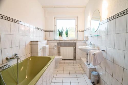 a bathroom with a green bath tub and a sink at Haus Mühlenbrock in Schermbeck