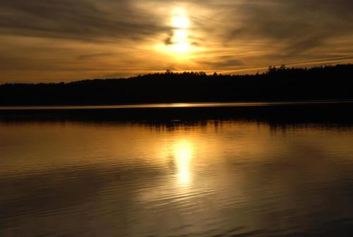 a sunset over a lake with the sun setting at Natura Apartamenty in Swaderki