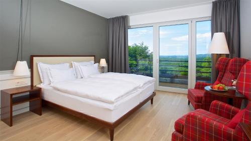 Habitación de hotel con cama y silla roja en Berghotel Tulbingerkogel en Mauerbach