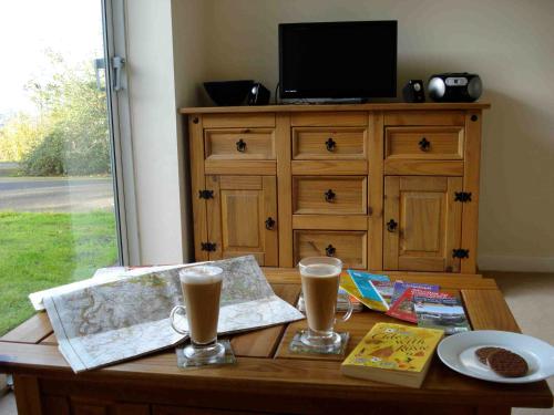 a wooden table with two glasses of beer and a tv at Bobby's Nook in Stroud