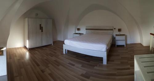 メレンドゥーニョにあるAppartamento Corte Incasili "A"のウッドフロアのベッドルーム1室(白いベッド1台付)
