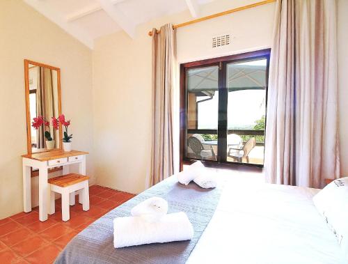 a bedroom with a bed and a table and a window at Lot 25 SM06 in Southbroom