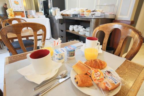 a table with a plate of breakfast food and orange juice at Grand Hôtel Des Gobelins in Paris