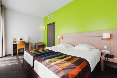 a bedroom with a large bed with a green wall at Esatitude Hotel in Nice