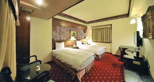 a hotel room with two beds and a television at KaRo Hotel in Kaohsiung