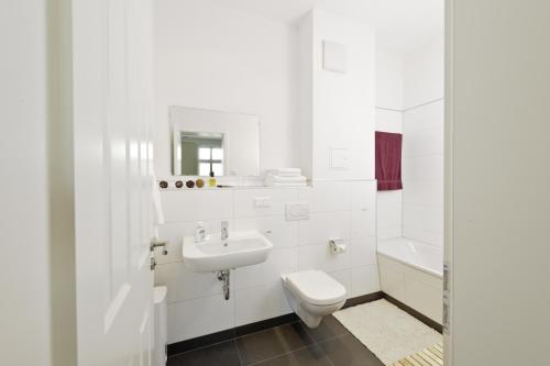 La salle de bains blanche est pourvue d'un lavabo et de toilettes. dans l'établissement City Park Boardinghouse - #25-30 - Freundliche Apartments, wahlweise mit Frühstück, im Zentrum, à Leipzig
