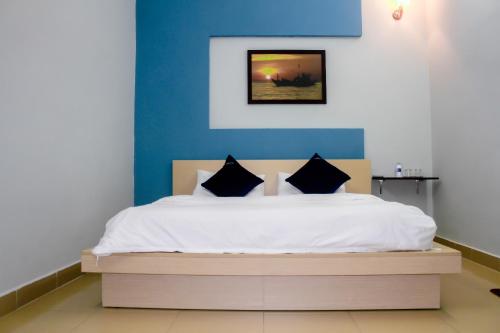 a bedroom with a white bed with a blue wall at Hana Homestay Danang in Danang