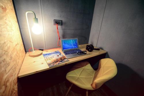 a desk with a laptop and a chair with a lamp at KID Hualien Hostel in Hualien City