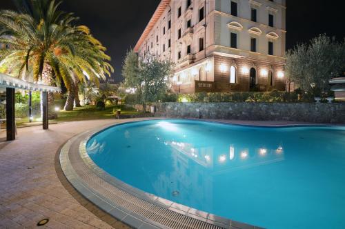 a swimming pool in front of a building at night at Grand Hotel Vittoria in Montecatini Terme