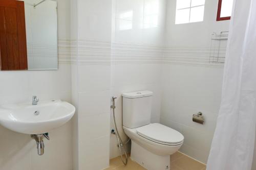a white bathroom with a toilet and a sink at Wattana House in Phetchaburi
