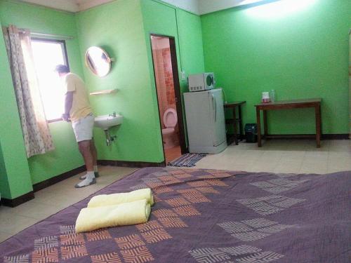 un hombre parado en un baño con una pared verde en Roong-Arun Apartment, en Bangkok