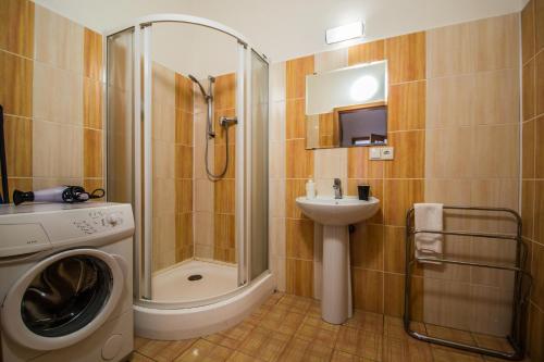 a bathroom with a shower and a sink and a washing machine at Modern Cozy Apartment by Ruterra in Prague