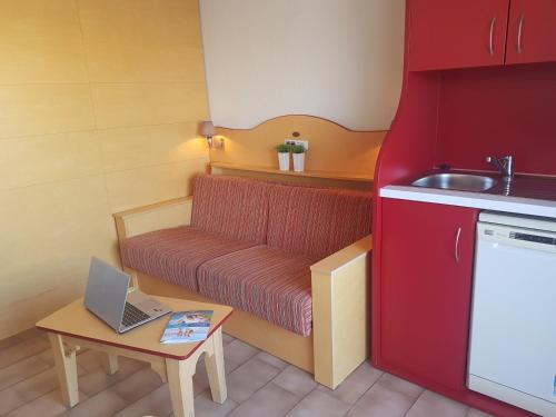 une petite cuisine avec un banc et un ordinateur portable sur une table dans l'établissement Résidence Goélia Aguylène, à Carnon-Plage