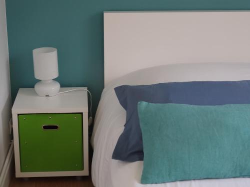 a bed with a green night stand next to a green pillow at Gite de l'Abbaye d'Etrun in Étrun