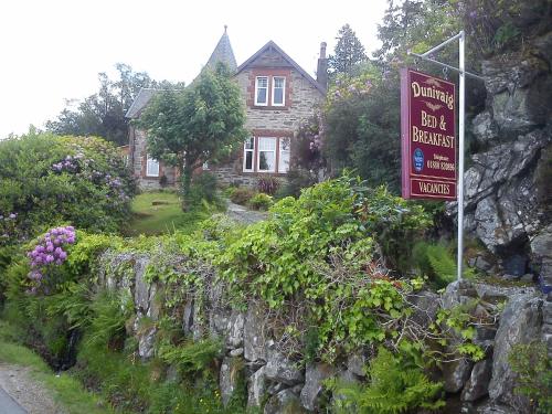 a sign on a stone wall in front of a house at Dunivaig B&B in Tarbert