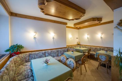a restaurant with tables and chairs and a couch at Hotel Bertoldi in Lavarone