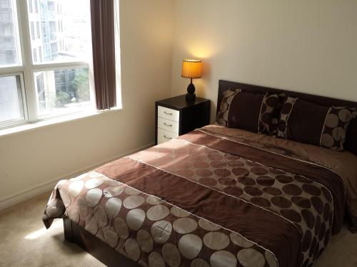 1 dormitorio con cama y mesita de noche con lámpara en 2 Bedroom 1 Bathroom Prime Location in Mississauga en Mississauga