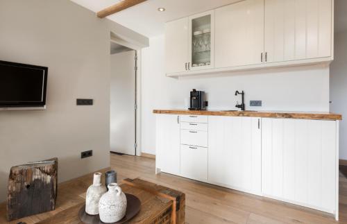 a kitchen with white cabinets and a wooden table at Bed & Breakfast de Zandhoef in Eersel