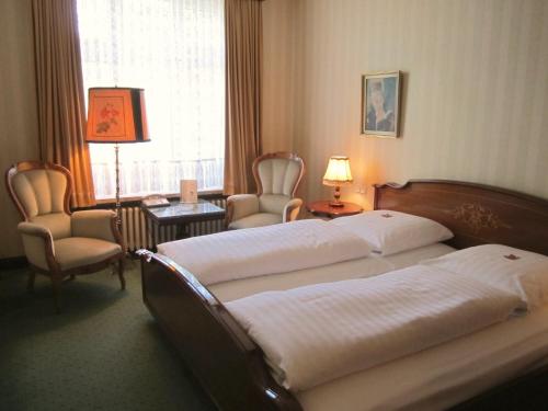 a hotel room with two beds and chairs and a window at Hotel Stephan in Hamburg