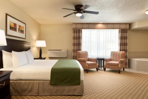 チャナッセンにあるCountry Inn & Suites by Radisson, Chanhassen, MNのベッドとバスタブ付きのホテルルームです。