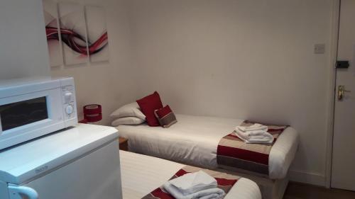 a small room with two beds and a microwave at Alexandra Guest House in Hemel Hempstead