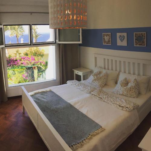 1 Schlafzimmer mit einem großen weißen Bett und 2 Fenstern in der Unterkunft Casa Matschinegg Madeira in Caniço