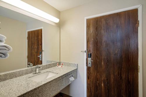 a bathroom with a sink and a wooden door at Super 8 by Wyndham Lexington Hamburg Area in Lexington