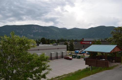 a parking lot with a building and mountains in the background at Canadas Best Value Inn & Suites-Castlegar in Castlegar