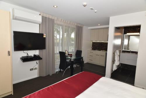 a bedroom with a bed and a desk and a television at 103 Prince of Bealey Motel in Christchurch