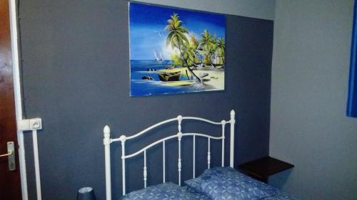 1 dormitorio con 1 cama y una pintura en la pared en Habitation Fouyapen, en Sainte-Anne
