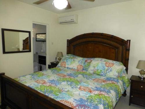 1 dormitorio con 1 cama con un edredón colorido en Rockley Golf Club, 2 bed 2 bath Pool, Tennis, Golf, Bar & Restaurant!, en Bridgetown