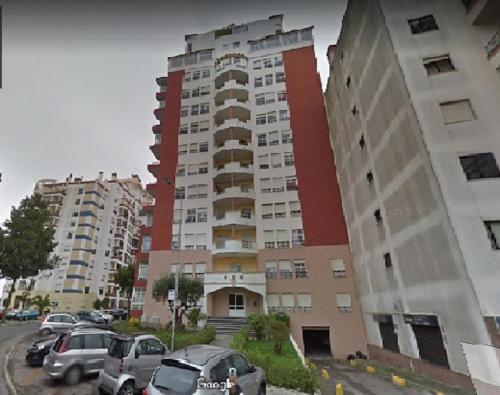 a tall building with cars parked in a parking lot at Lisa House in Sintra