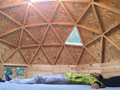un hombre acostado en una cama en una habitación con techo en Kamp Nattivo, en Sutatausa