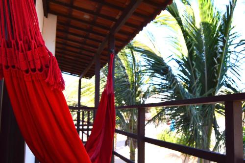 a red hammock hanging from a balcony with a palm tree at Pousada Atlantis in Jericoacoara