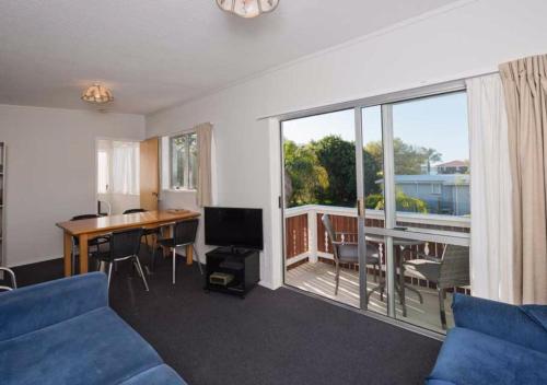 a living room with a couch and a table and a balcony at Edelweiss Motel in Paihia