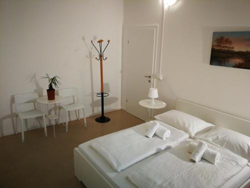 a white bedroom with a bed and a table at Central Rooms in Bolzano