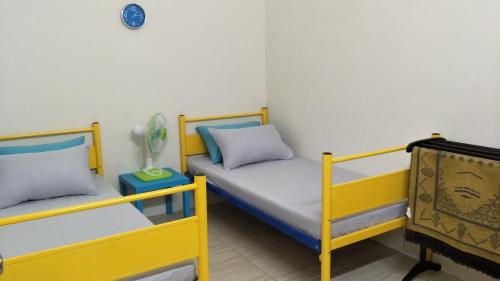 Zimmer mit 2 Betten und einer Uhr an der Wand in der Unterkunft Airis Homestay Changlun in Changlun