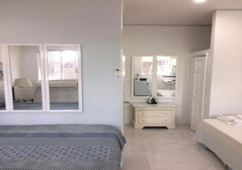 a white bedroom with a bed and a mirror at The Oasis Retreat in Nassau