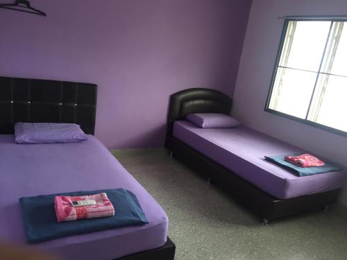 Duas camas num quarto com paredes roxas e uma janela em Apple Boutique Homestay em Kuantan